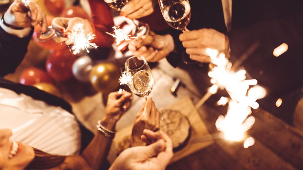 Friends celebrating New Year’s Eve with champagne glasses and sparklers at a festive party
