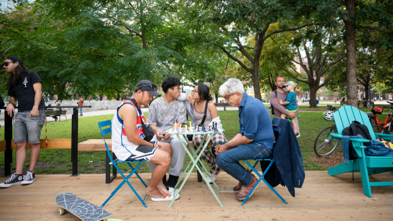 People playing chess at The Deck at Clarence Square in Downtown West Toronto, with outdoor seating and greenery