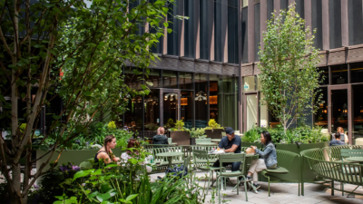 Outdoor patio seating at Waterworks Food Hall surrounded by greenery and modern buildings in downtown Toronto.